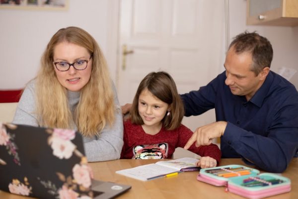 A family is engaged in homeschooling, using technology to learn together in a cozy home setting.